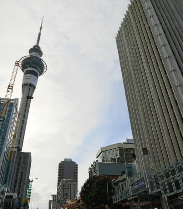 Sky Tower and surrounding buildings under a cloudy sky in Auckland city.
