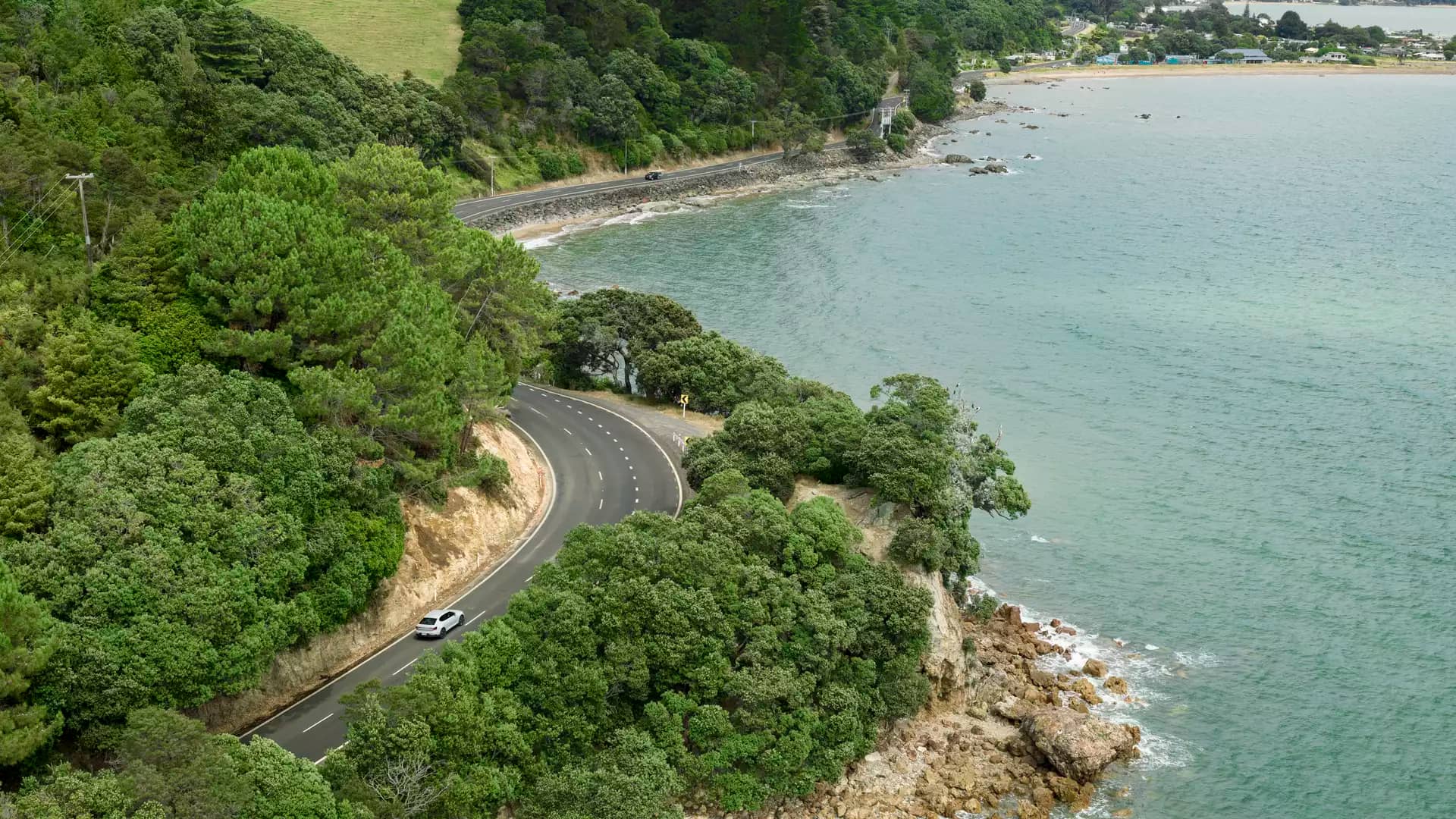 Car driving alongside Thorton Bay in the Coromandel