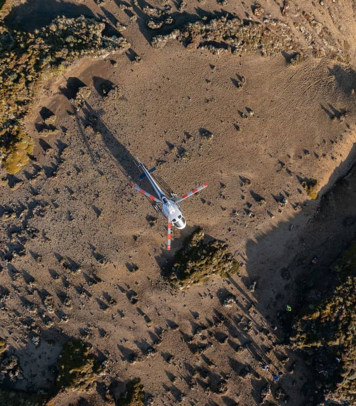Helicopter surrounded by volcanic landscape.